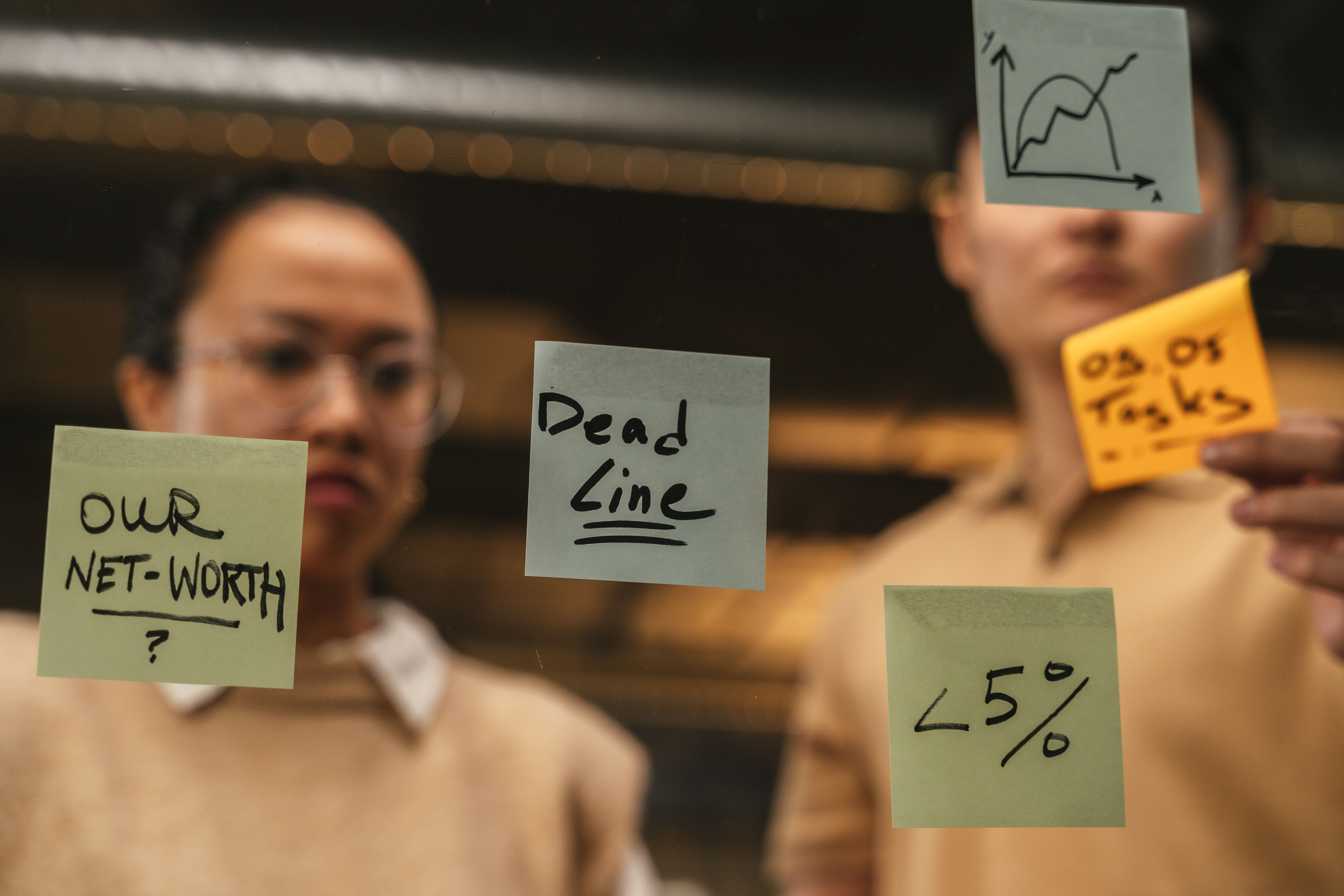 Sticky notes mapping deadlines, tasks, and targets on a glass wall